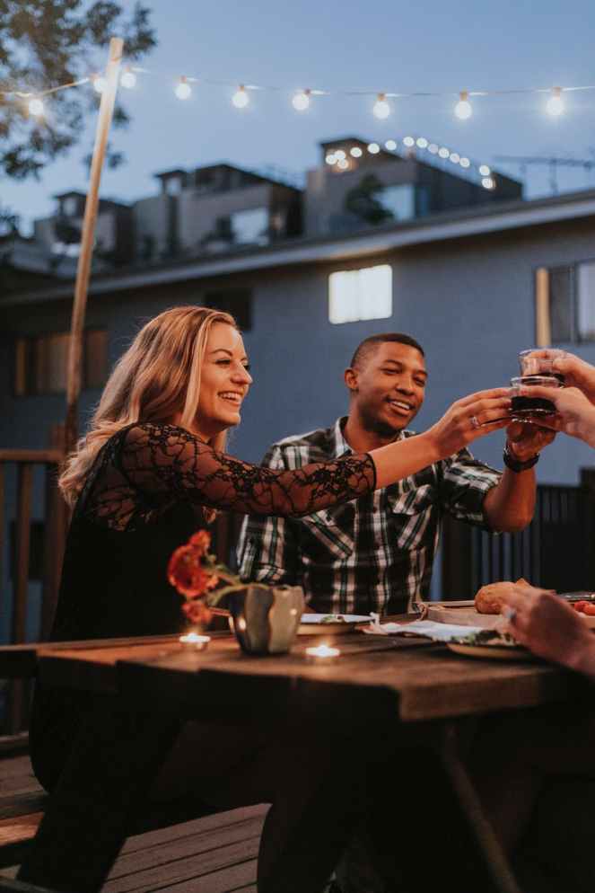 woman and man cheering glass cup beside table during night time