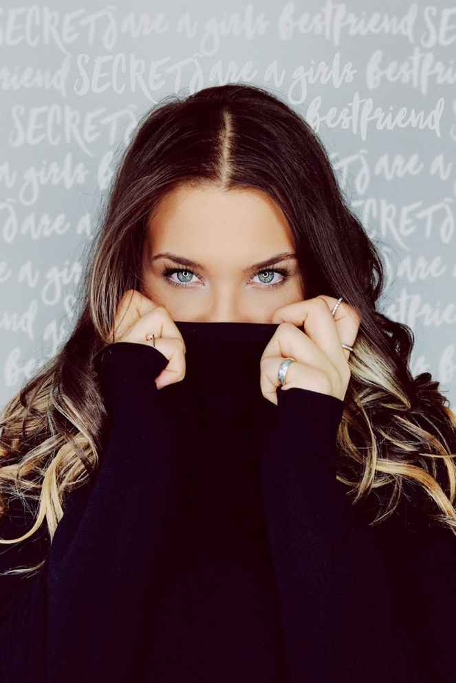 woman in purple sweater covering her face