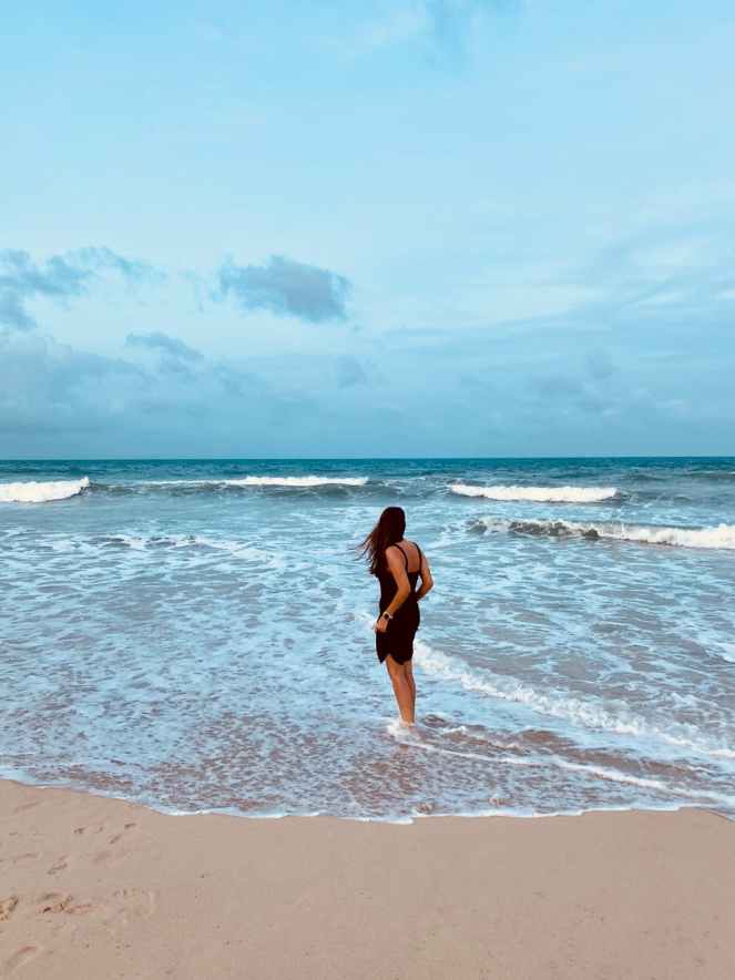 woman in black dress walking on beach