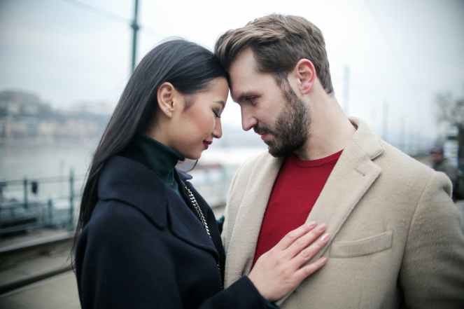 happy multiracial couple hugging on waterfront while having romantic date in city