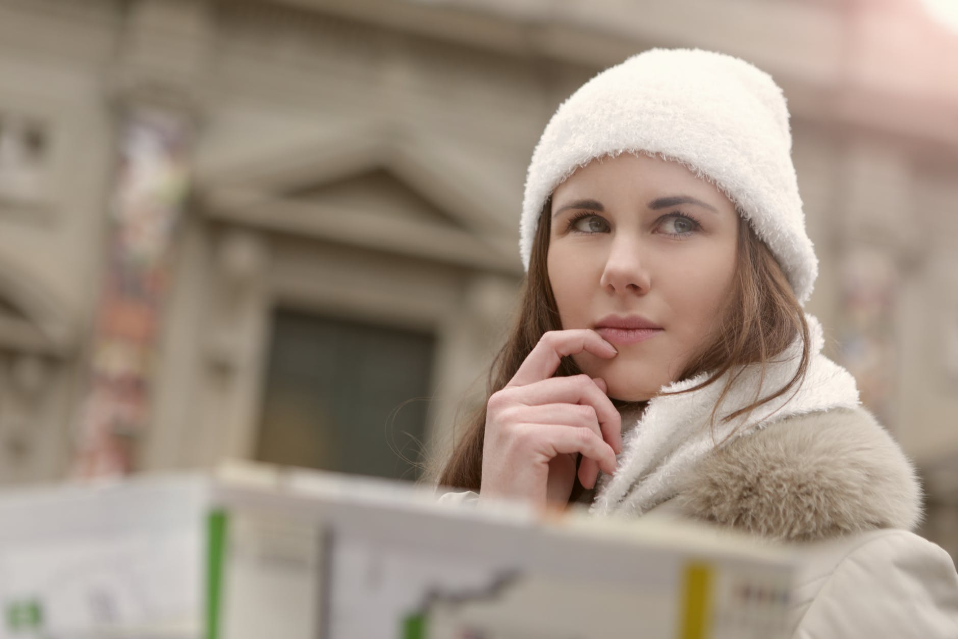 young lady in warm wear thinking in city street